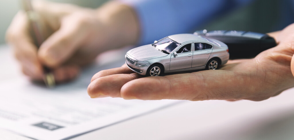 buy new car concept - scale model and key in dealer hand