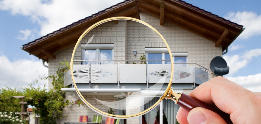Person Hand With Magnifying Glass Over Luxury House