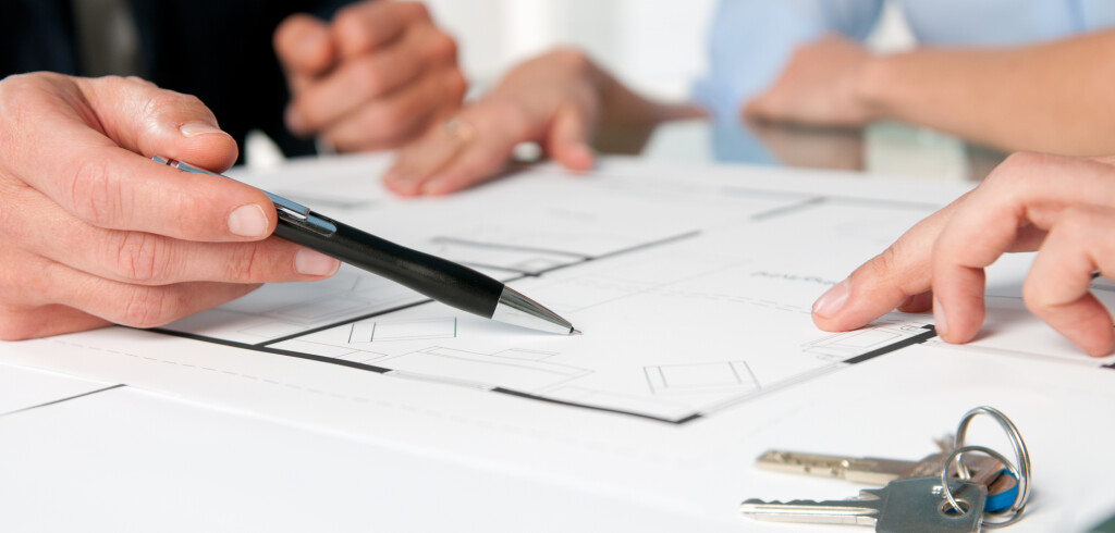 Closeup view of new home keys and house plan during a discussion with a real estate agent