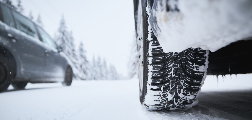 Close-up view of tire of car on snow covered and icy road. Themes safety and driving in winter.