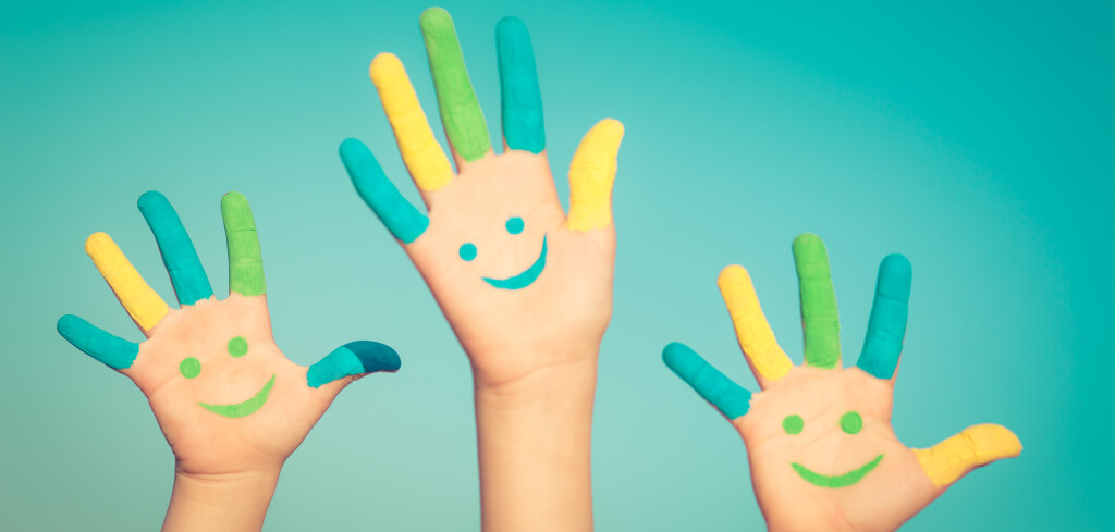 Happy children with smiley on hands against blue summer sky background